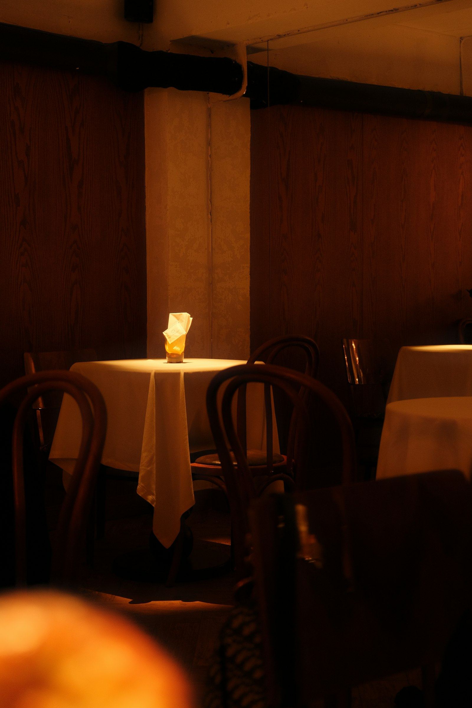 A single candlelit table glowing amid Meridian's dimly lit dining room