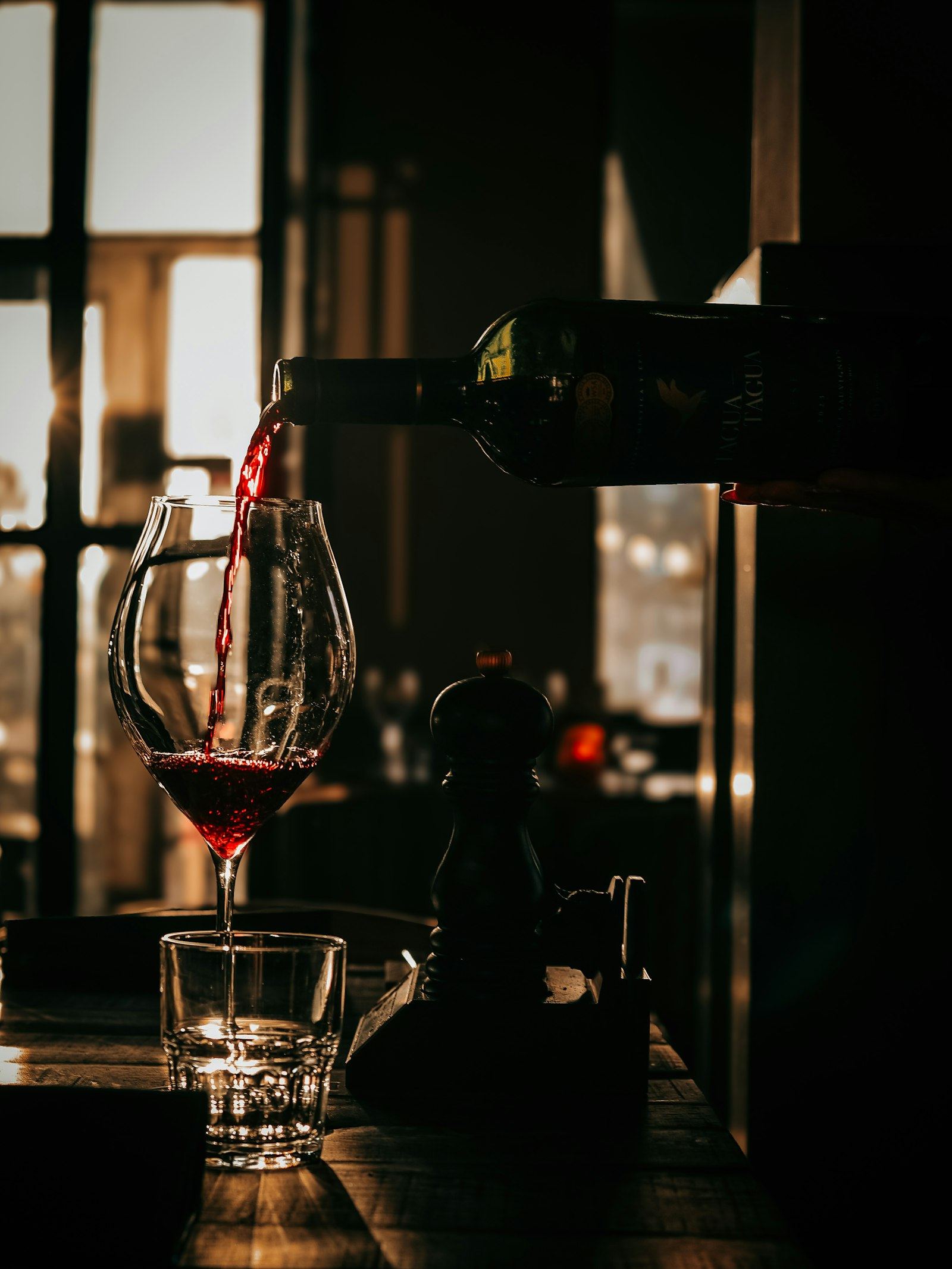 Red wine being poured into a glass at the table