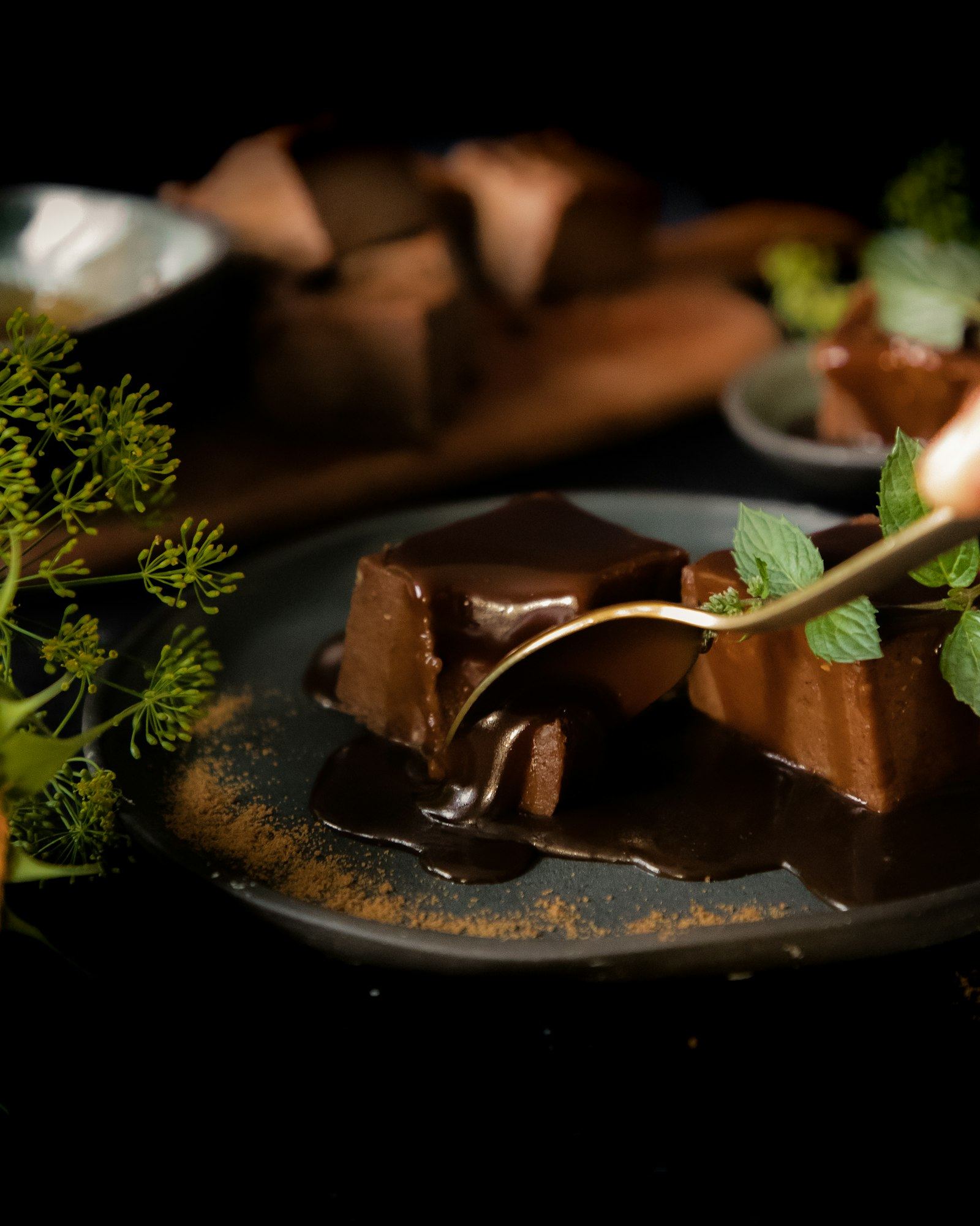 Dark chocolate dessert with sauce, plated on black ceramic